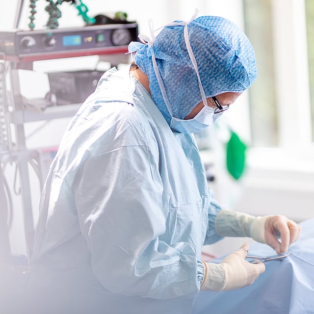 En person som bär kirurgutrustning och handskar.