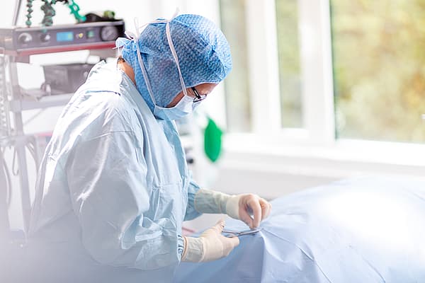 En person som bär kirurgutrustning och handskar.