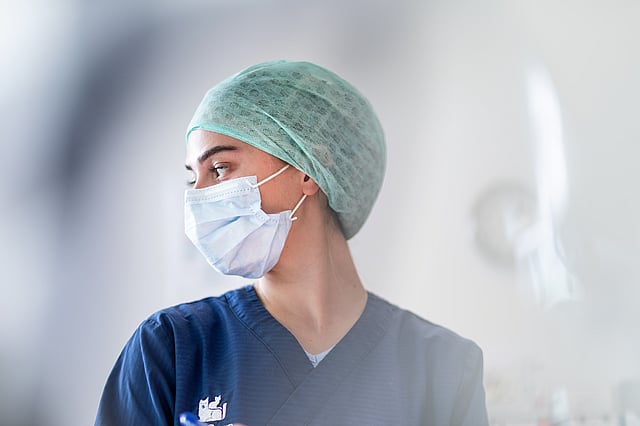 A person wearing a surgical mask and scrubs.